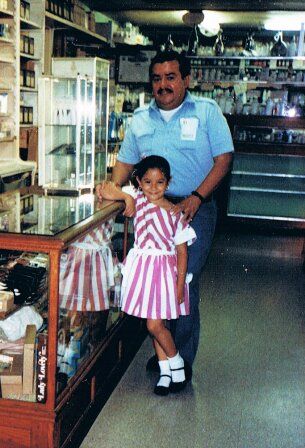 Victor C. Ortiz with his young daughter Alejandra inside the pharmacy, 1988